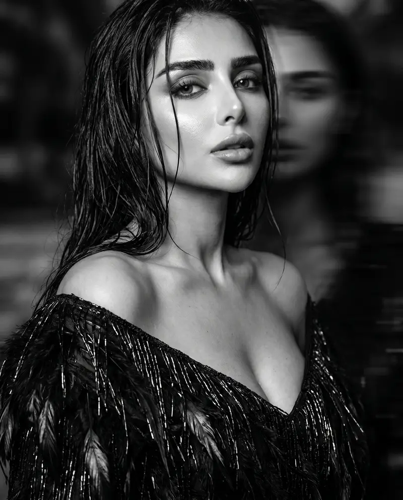 Low-key portrait in a feathered black dress, a second exposure blurred behind